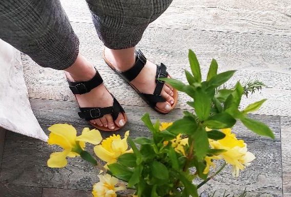 Crne sandale kraj žutog cvijeća.