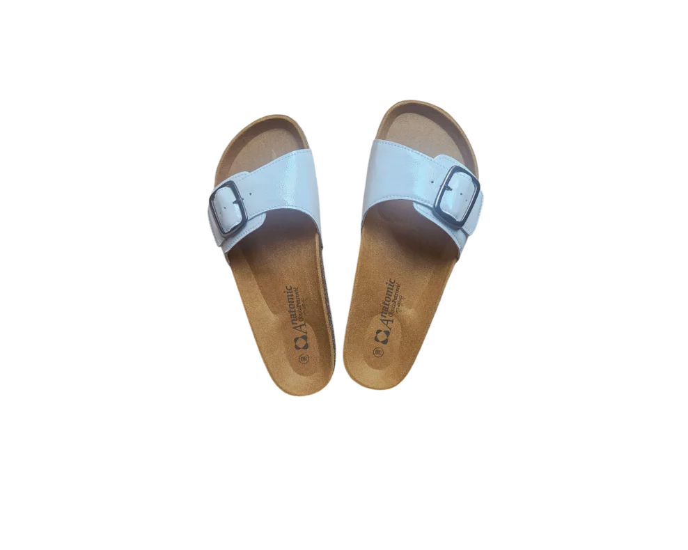 Ženske bijele lakirane papuče s plutenim đonom naslagane jedna na drugu, prikaz teksture lakirane kože.