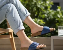 Žena nosi tamnoplave kožne natikače s mramornim uzorkom uz svijetle traperice na sunčanoj terasi